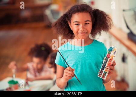 Fille afro-américaine tenant un pinceau et aquarelle Banque D'Images