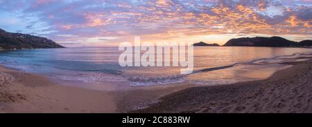 Vue panoramique sur les magnifiques tons pastel orange et or coucher de soleil nuages et vagues au bord de la mer Agios Georgios Pagon plage sur l'île de Corfou, Grèce Banque D'Images