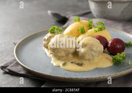 Koenigsberger Klopse ou boulettes de viande dans une sauce au béchamel blanc avec câpres, pommes de terre et betteraves servies sur une assiette bleue grise, polonais traditionnel et fer Banque D'Images