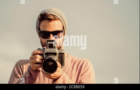 Le photojournaliste concept. Billet d'un blogueur. Photographe professionnel. Photographe guy beau appareil photo rétro. Guy photographe en plein air fond de ciel. Journaliste de prendre photo. Hipster Des réglages manuels. Banque D'Images