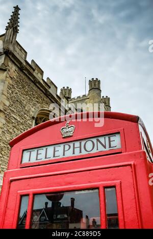 Vue rapprochée du toit d'une ancienne boîte téléphonique rouge britannique, montrant le lettrage et la couronne peinte en or sur le toit. Banque D'Images