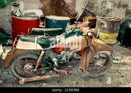 Cycles de vie indésirables abandonnés. Les motos de style rétro ancien sont utilisées avec des fûts d'huile et autres déchets dans les décharges sanitaires. Image de stock Banque D'Images