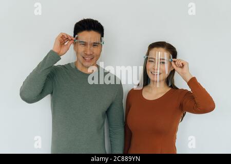 Homme et femme chinois souriant et portant des revêtements de visage personnels de protection Banque D'Images