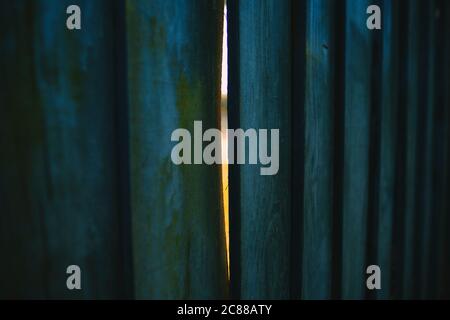 Une clôture en bois peinte en bleu avec une fente de lumière venir à travers - sliver de la lumière - sliver de l'espoir Banque D'Images