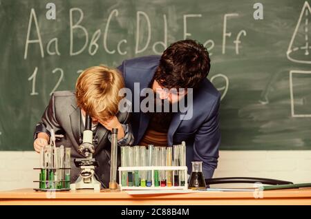 Nous avons une appréciation pour l'innovation, fils et père à l'école. Sagesse. Retour à l'école. Chimie et biologie physique. Fiole dans la main scientifique avec tubes à essai. Petit garçon avec professeur. Banque D'Images