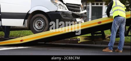 Un minibus accidenté est chargé sur un camion de remorquage après un accident. Banque D'Images