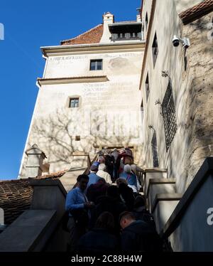 Touristes attendant en que à l'entrée principale pour aller à l'intérieur du château de Bran. Ancien manuscrit ci-dessus, mur extérieur du château de Bran. Banque D'Images