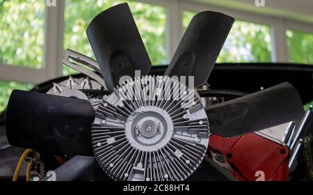 Roue de ventilateur d'un moteur V8 intégré dans une coque de carrosserie d'une voiture de muscle. En gros plan. Banque D'Images