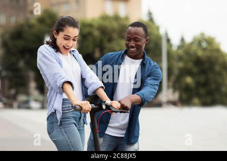 Guy et fille ayant porté sur le scooter électrique de coup Banque D'Images