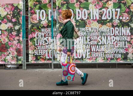 Femme marchant devant une bannière colorée à Bâle Banque D'Images
