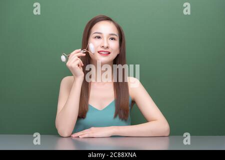 Femme saine de peau utilisant un rouleau de visage de quartz sur sa peau impeccable. Banque D'Images