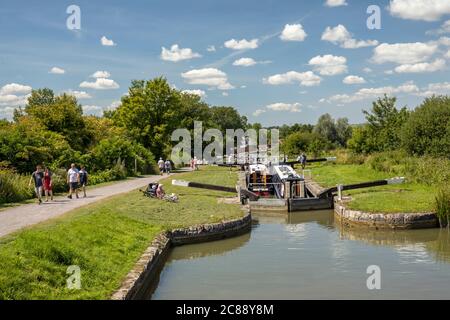 Deux bateaux étroits côte à côte à l'écluse 31 de Caen Hill Locks, Devizes, Wiltshire, Angleterre, Royaume-Uni, tandis que les familles marchent sur la voie de remorquage Banque D'Images