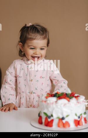 Une petite fille adorable et un vieux vieux vieux de hulf stand par un délicieux gâteau d'anniversaire. Fille de dix-huit mois très heureuse et rires. Plats végétariens. Lactose Banque D'Images