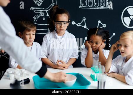 Curieux adorables enfants adorables étudiant les processus chimiques à l'école primaire, travaillant sur un projet de groupe tout en se tenant et regardant la réaction de la Twin Banque D'Images