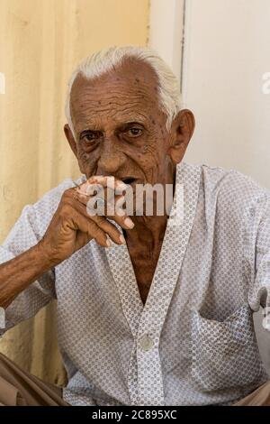 La Havane / Cuba - 04.15.2015: Gros plan d'un vieil homme cubain assis dans la rue, fuyant un cigare dans la vieille ville, la Havane, Cuba Banque D'Images