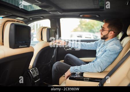 un homme attrayant est assis sur la voiture et montre le chemin à un chauffeur. il pointe vers la rue, la maison. adresse et destination concept. vue latérale Banque D'Images