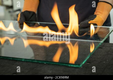 Le vitrier coupe le verre de sécurité, VSG (verre très sûr) le feu brûle à travers le film reliant les panneaux, UNE technique spécialisée de découpe du GL laminé Banque D'Images