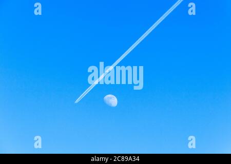 Un avion avec contrail passant la lune de gibbous de cire dans un ciel bleu clair un après-midi d'été, Londres, Royaume-Uni Banque D'Images