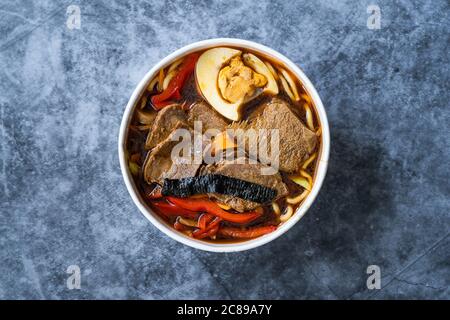 Enfourchez le coolé Shoyu Ramen avec œufs, pousses de soja, viande de veau, carotte, oignon, wakame d'algues, radis japonais et sauce soja dans un bol en plastique. T sain Banque D'Images