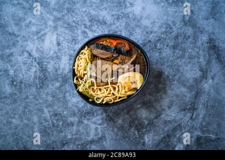 Croque de Shoyu Ramen avec œuf, pousses de soja, viande de veau, carotte, oignon, wakame d'algues, radis japonais et sauce de soja. Restauration rapide traditionnelle saine. Banque D'Images