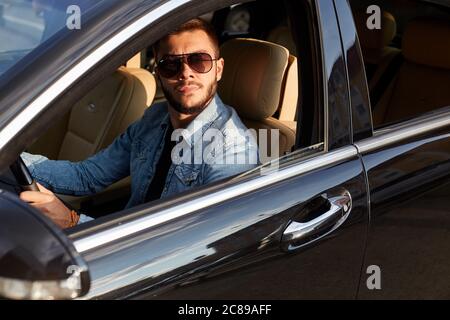 un homme attrayant est assis dans le véhicule de luxe. gros plan vue latérale photo. Banque D'Images