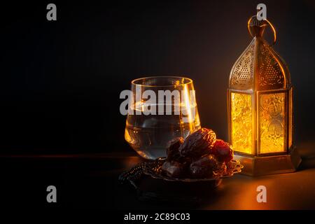Tradition religieuse musulmane, mois Saint du Ramadan, Islam et Iftar concept thème avec un bol de dates, perles de prière, verre d'eau et lanterne arabe Banque D'Images