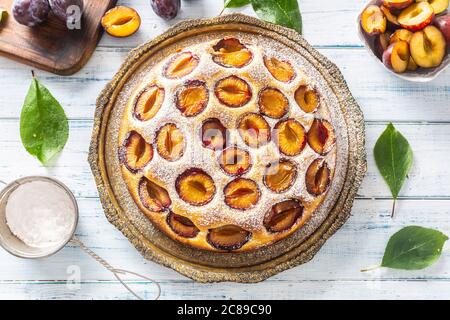 Gâteau aux prunes maison dans une assiette vintage sur une table en bois. Tarte aux prunes avec sucre en poudre Banque D'Images