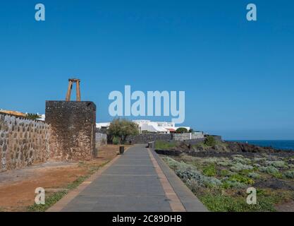 Vue sur la promenade piétonne le long de la plage de Los Cancajos avec vieux mur en pierre de lave, appartements blancs, arbres et fond bleu ciel. La Palma Banque D'Images