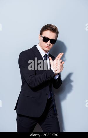Espionner le policier criminel détective homme avec un pistolet dans un costume de classe avec cravate et lunettes de soleil, debout et posant isolé sur fond pur Banque D'Images