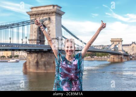 Bonne jeune femme bras élevés à Chain Bridge, Budapest, Hongrie Banque D'Images