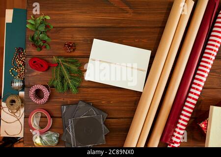 Vue en grand angle de la boîte cadeau blanche non emballée sur la table en bois sombre avec papier d'emballage, boules de ficelle décorant des éléments vacances et cadeaux conc Banque D'Images