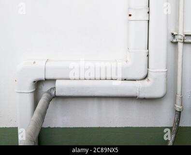 Couvercle de tuyauterie en plastique blanc sur le fil électrique du système de climatisation sur le mur en béton de bureau. Banque D'Images