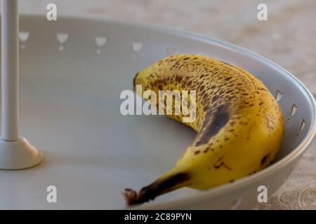 Banane mûre dans un bol de fruits blanc métallisé décoré de petits coeurs Banque D'Images