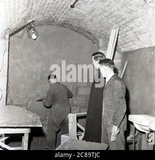 Années 1960, historique, prêtre avec des ouvriers qui entreprennent des réparations à la crypte, à l'église St. Pauls, Deptford, sud-est de Londres. Dans les années 1980, le sous-sol était le lieu de raves et de gigas, y compris le groupe, les Roses de pierre Banque D'Images