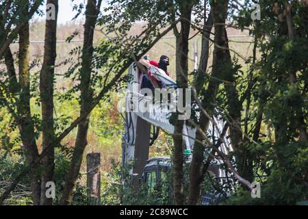 Harefield, Royaume-Uni. 22 juillet 2020. Un activiste de la rébellion HS2 occupe une machinerie lourde pour retarder l'abattage des arbres de la HS2 le long de Harvil Road. Plusieurs activistes environnementaux ont occupé des machines et des arbres pour protester contre la liaison ferroviaire à grande vitesse, qui devrait actuellement coûter 106 milliards de livres sterling et rester un contributeur net aux émissions de CO2 pendant sa durée de vie prévue de 120 ans. Crédit : Mark Kerrison/Alamy Live News Banque D'Images