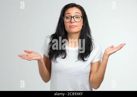 gros plan portrait d'une jolie femme en lunettes haussant les épaules isolées sur un fond blanc. Je ne sais pas. Concept d'indifférence Banque D'Images