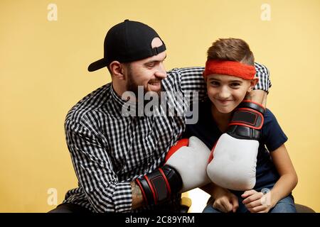 Père et fils s'amusant et se portant avec des gants de boxe isolés sur fond jaune Banque D'Images