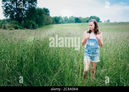 Jeune fille debout dans une prière gravieuse lors d'une journée d'été. Banque D'Images
