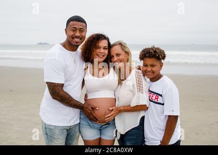 Famille posant pour des photos de maternité sur la plage Banque D'Images