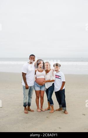 Famille posant pour des photos de maternité sur la plage Banque D'Images