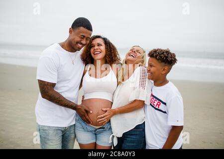 Famille posant et riant pour des photos de maternité sur la plage Banque D'Images