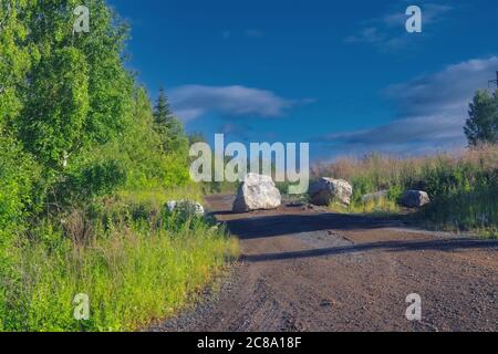 Boulder bloque un chemin de forêt. Sur un chemin de forêt se trouve une grande roche qui bloque le chemin. Banque D'Images
