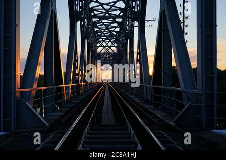 Pont ferroviaire sur la rivière le soir au coucher du soleil Banque D'Images