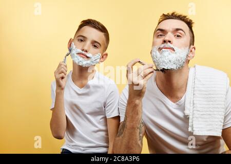 Le père et le fils barbu se rasant sur fond jaune Banque D'Images