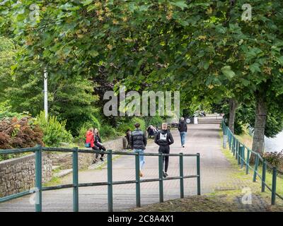 Les gens qui marchent et s'assoyent sur le sentier bordé d'arbres au bord de la rivière Ness. Ness Walk, Inverness, Écosse Banque D'Images