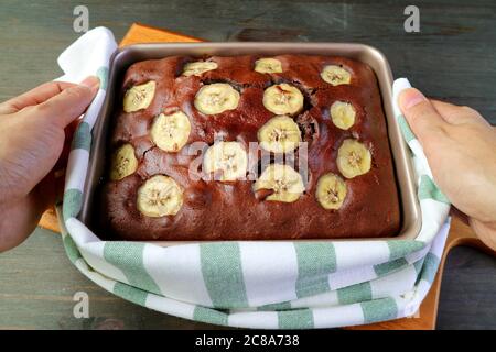 Main tenant une casserole de délicieux gâteau au chocolat chaud maison à l'huile d'olive Banana Banque D'Images