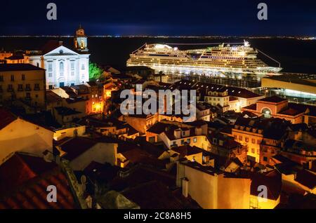 Vue nocturne de Lisbonne (Portugal) port de bateaux de croisière depuis le miraduro de Santa Luzia, terrasse belvedere sur les rues du quartier d'Alfama, avec le ch Banque D'Images