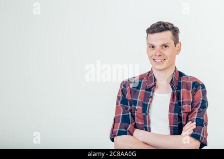 Jeune homme heureux. Portrait d'un jeune homme beau en chemise décontractée, en gardant les bras croisés et en souriant Banque D'Images