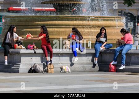 Londres, Royaume-Uni. 22 juillet 2020. Un groupe de jeunes ont un peu de normalité avec des plats à emporter près de la fontaine. Les gens apprécient aujourd'hui le beau soleil et les températures chaudes autour de Trafalgar Square à Londres. Crédit : Imagetraceur/Alamy Live News Banque D'Images