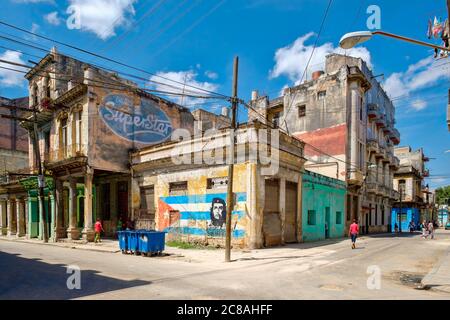 Scène de rue avec des gens et des vieux bâtiments en décomposition à la Havane avec une image de Che Guevara et un drapeau cubain peint sur un Banque D'Images